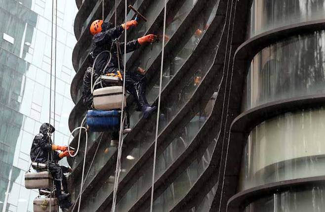 로프를 이용해 건물 외벽을 청소하고 있는 작업자들. 올해 상반기에만 산업 재해로 사망한 20~30대 청년은 113명이다. / 장련성 기자
