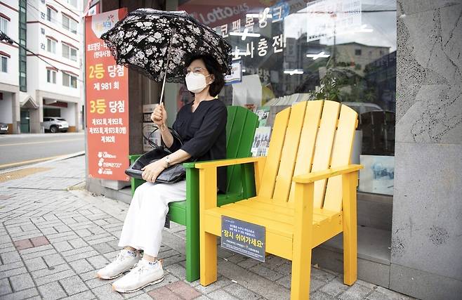 부산 금정구 남산동 현대서점 앞에 설치된 ’기억채움 동행인’ 의자에 주민이 앉아서 쉬고 있다. 금정구 제공