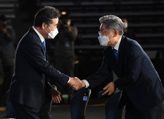 더불어민주당 이재명 대선 경선 후보가 10일 오후 서울 송파구 올림픽공원 SK올림픽핸드볼경기장에서 열린 제20대 대통령선거 후보자 선출을 위한 서울 합동연설회에서 이낙연 후보와 악수하고 있다.연합뉴스