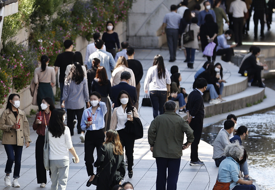 Office workers stroll along the Cheonggye stream in central Seoul on Wednesday during their lunch break. According to Statistics Korea, there were 671,000 more people employed in September, up 2.5 percent year-on-year, despite the spread of Covid-19 variant continuing. [YONHAP]