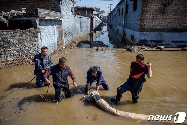 (진중 AFP=뉴스1) 금준혁 기자 = 11일(현지시간) 중국 산시성에 쏟아진 집중호우로 인해 홍수가 발생해 구조대원들이 도시에서 물을 빼내고 있다. (C) AFP=뉴스1