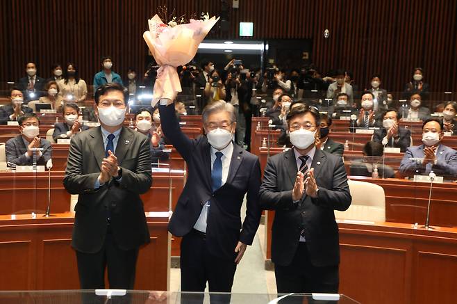 15일 오전 서울 국회에서 열린 더불어민주당 의원총회에 참석한 이재명 대선 후보가 윤호중 원내대표가 준 꽃다발을 들어보이며 대선승리를 다짐 하고 있다. 2021.10.15 국회사진기자단