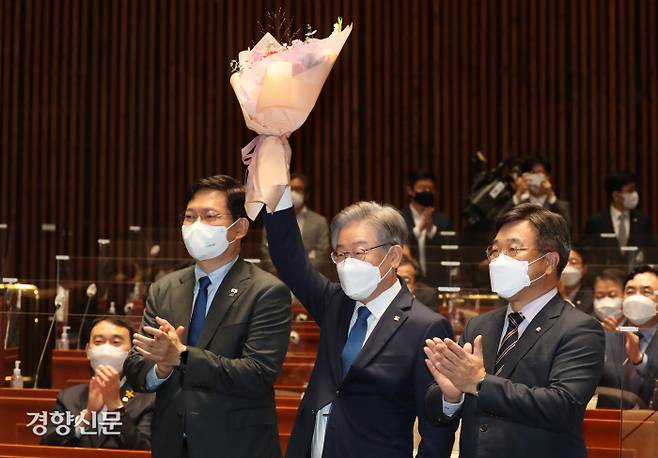 이재명 대선 후보가 15일 오전 서울 여의도 국회 예결위회의장에서 열린 더불어민주당 의원총회에서 윤호중 원내대표에게 받은 꽃다발을 들고 있다. 왼쪽부터 송영길 대표, 이 후보, 윤 원내대표.  국회사진기자단