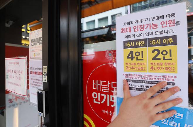 지난 9월 서울 종로구의 한 식당에서 직원이 내일부터 적용되는 새로운 사회적 거리두기 지침 관련 안내문을 부착하고 있다. (사진=연합뉴스)