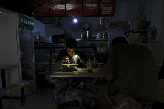 극심한 전력난을 겪고 있는 중국 북동부 랴오닝성 선양의 한 식당에서 지난달 29일 정전사태가 빚어지자 한 남성이 휴대전화 불빛에 의지해 아침 식사를 하고 있다. [이미지출처=연합뉴스]