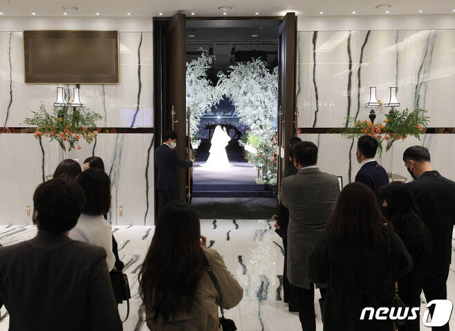 17일 서울의 한 예식장에서 시민들이 식장 밖에서 결혼식을 바라보고 있다. 새로운 사회적 거리두기 조정안에 따라 오는 18일부터 결혼식은 3~4단계에서 식사 여부에 관계없이 최대 250명까지 참석 가능하다./뉴스1 © News1 신웅수 기자