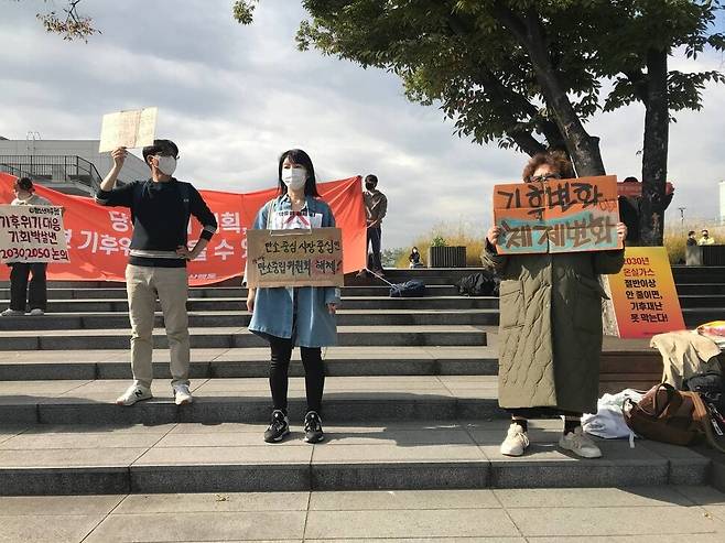 19일 대통령 소속 ‘2050 탄소중립위원회’가 탄소중립 시나리오 최종안을 공개하자 탄소중립위원회 해체와 기후정의 실현을 위한 공동대책위원회 회원들이 탄중위 회의가 열린 서울 용산구 노들섬 앞에서 반대 피켓을 들고 항의하고 있다. 탄중위해체공대위 제공