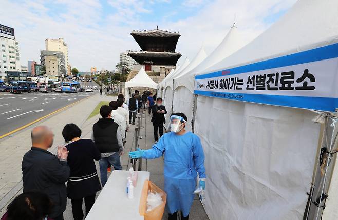 18일 오전 서울 종로구 흥인지문 옆에 설치된 찾아가는 선별검사소에서 코로나19 집단감염이 발생한 동대문 인근 시장 종사자들이 검사를 받기 위해 대기하고 있다. 연합뉴스