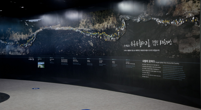 태안 유류피해극복기념관 한쪽 벽면에 전시된 기름 유출 사고 당시 방제 작업에 나선 자원봉사자들의 사진. 자원봉사자들은 인간띠를 이뤄 기름을 제거했다.