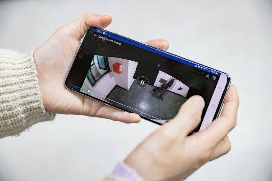 핸드폰을 통해 문 앞 CCTV 화면을 보고 있는 모습