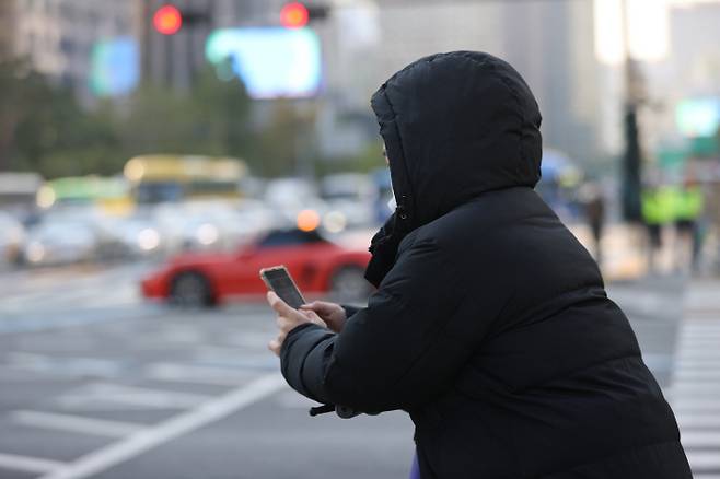 아침 기온이 5도까지 내려가 쌀쌀한 날씨를 보인 20일 오전 서울 종로구 광화문네거리에서 두꺼운 외투를 입은 시민이 횡단보도 신호를 기다리고 있다. [사진 출처 = 연합뉴스]