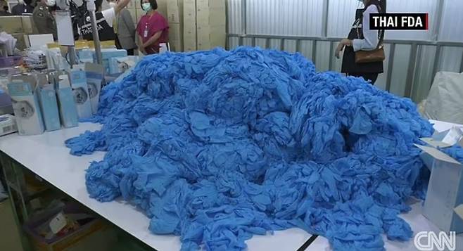 태국 불법창고에서 새것으로 둔갑 중이던 의료용 니트릴장갑 발견. 이미 사용했던 흔적이 역력한 이 장갑은 파란색 물감으로 염색된 뒤 새것으로 둔갑해 전 세계로 다시 수출됐다. 사진=CNN 영상