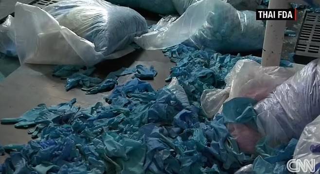 태국 불법창고에서 새것으로 둔갑 중이던 의료용 니트릴장갑 발견. 이미 사용했던 흔적이 역력한 이 장갑은 파란색 물감으로 염색된 뒤 새것으로 둔갑해 전 세계로 다시 수출됐다. 사진=CNN 영상
