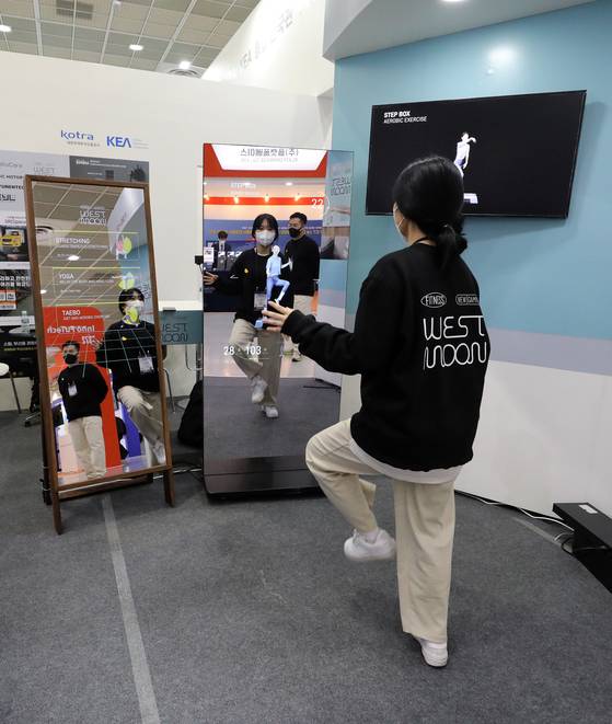 An employee of West Moon, a digital health care company, demonstrates a display that gives a workout regime during the Korea Electronics Show on Tuesday at Coex in Gangnam District, southern Seoul. Some 400 electronics companies including Samsung Electronics and LG Electronics are participating in the country’s biggest electronics event that runs through Oct. 29. [NEWS1]