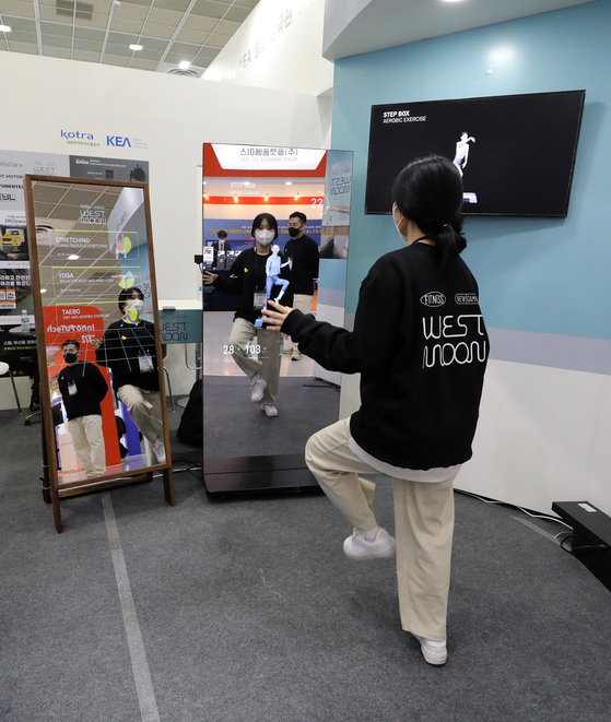 An employee of West Moon, a digital health care company, demonstrates a display that gives a workout regime during the Korea Electronics Show on Tuesday at Coex in Gangnam District, southern Seoul. Some 400 electronics companies including Samsung Electronics and LG Electronics are participating in the country’s biggest electronics event that runs through Oct. 29. [NEWS1]