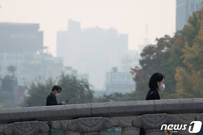 중국발 미세먼지 유입 등으로 일부지역에 미세먼지 농도가 '나쁨' 수준을 보인 27일 오전 서울 청계천 일대를 지나는 시민들 뒤로 도심이 뿌옇게 보이고 있다. 기상청은 중부지방에서 오전에, 남부지방에서 오후에 미세먼지 농도가 높아질 것으로 전망했다. 2021.10.27/뉴스1 © News1 유승관 기자