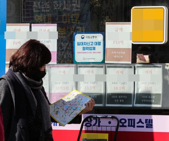 서울 서대문구의 부동산 중개업소에 게시된 매물 가격 안내판 앞에서 한 시민이 주변 아파트를 소개하는 안내도를 살펴보고 있다. <연합뉴스>