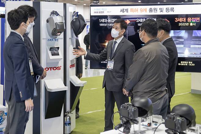 서울 삼성동 서울 코엑스에서 26일부터 29일까지 열리는 2021 스마트비즈엑스포에 참가한 안면보호구 생산기업 오토스윙의 허문영 대표(가운데)가 삼성전자 관계자들과 개발중인 제품에 대해 논의하고 있다.