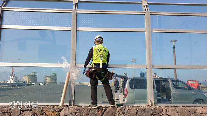 제주 애월항에서 27일 한 작업자가 투명 방진벽에 조류 충돌 방지를 위한 특수필름을 설치하고 있다. 박미라 기자