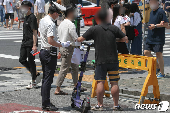 서울 시내에서 경찰이 헬멧을 미착용한 공유형 전동 킥보드를 이용자를 단속하고 있다. 2021.6.13/뉴스1 © News1 성동훈 기자