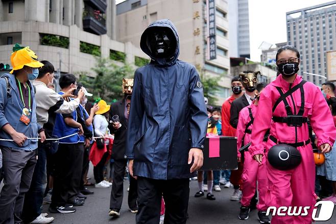 30일 대만의 타이베이에서 젊은이들이 오징어게임 경비원과 프런트맨 복장을 입고 행진을 하고 있다. © 로이터=뉴스1 © News1 박형기 기자