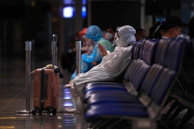 지난달 15일 베트남 호찌민의 떤선넛 국제공항 출국 대기구역에서 한 탑승객이 전신 방호복을 입은 채 비행기를 기다리고 있다. 호찌민=AP 연합뉴스