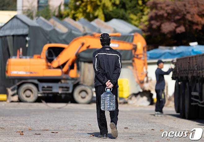 요소수 공급 부족이 지속되고 있는 7일 오전 서울 양천구 서부트럭터미널에서 화물차 기사가 요소수를 구하지 못해 빈 통을 들고 되돌아가고 있다. 요소수 공급난은 중국이 원료인 요소의 수출을 제한했기 때문인데 사실상 중국이 수출 규제를 풀지 않을 경우 지금과 같은 공급난이 수개월 이상 이어질 것이라는 전망이 나온다. 정부가 중국과의 협상을 통해 수입을 늘리고 수입선을 다변화 하는 등 대책을 내놨지만 수급난을 해소하기에는 상당한 시일이 걸릴 것으로 예상된다. 2021.11.7/뉴스1 © News1 이재명 기자