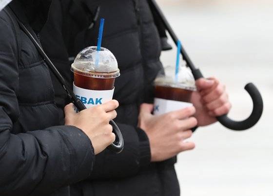 비가 내리며 쌀쌀한 날씨를 보인 9일 서울 종로구 광화문 일대에서 시민들이 아이스 커피를 들고 출근하고 있다. 뉴스1