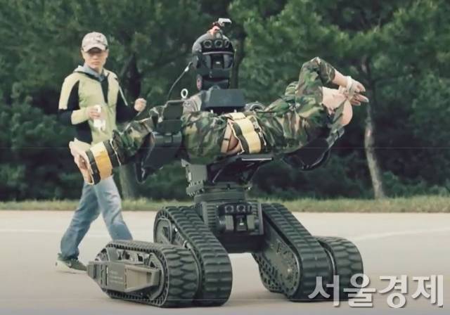 '민군겸용기술' 사업의 일환으로 개발이 추진된 구난용 로봇이 두 팔에 부상자(마네킹)을 들고 이동하고 있다. ADD의 주관 하에 한국기계연구원, DGIST, 한화, 로보스타 등 11개 민관기관이 참여해 민수용과 군용으로 다양하게 활용할 수 있도록 개발했다./ADD 홍보동영상 캡처