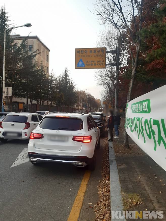 어린이 보호구역 표지판 아래 줄지어 불법 주차를 하고 있다. 사진=명정삼 기자.