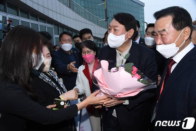 (파주=뉴스1) 국회사진취재단 = 윤석열 국민의힘 대선후보가 19일 경기 고양시 일산 킨텍스에서 열린 '2021 케이-펫페어(K-PET FAIR)일산' 행사에 참석해 지지자로부터 꽃다발을 받고 있다. 2021.11.19/뉴스1