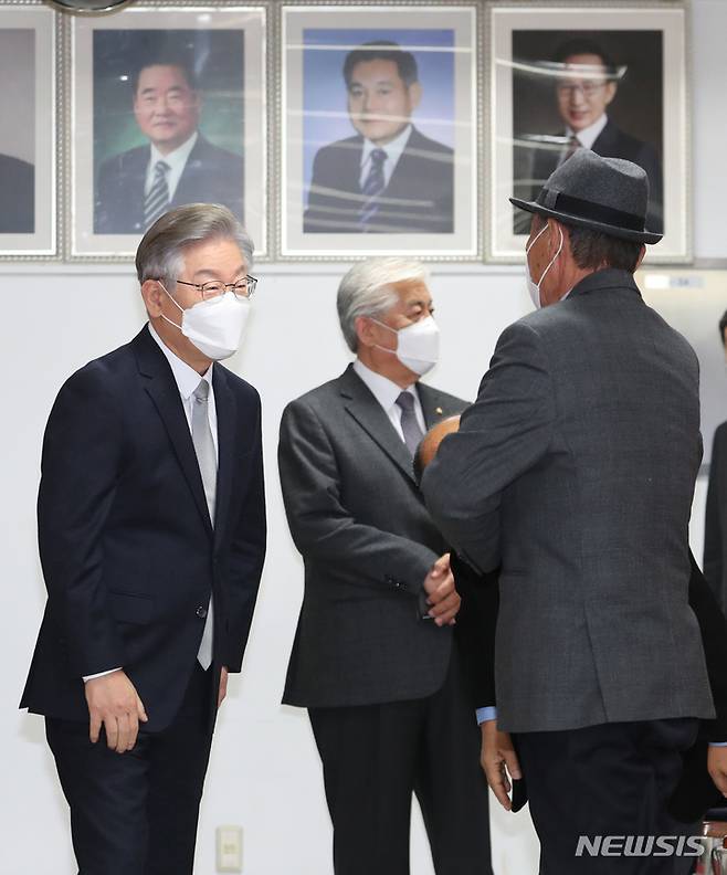 [서울=뉴시스] 국회사진기자단 = 이재명(왼쪽) 더불어민주당 대선 후보가 19일 오전 서울 종로구 경주이씨중앙화수회관에서 열린 제29대 5차 상임회장단회의에서  참석자들과 인사를 나누고 있다. 회의실 벽면에 이건희 전 삼성회장과 이명박 전 대통령의 액자가 걸려 있다. 2021.11.19. photo@newsis.com