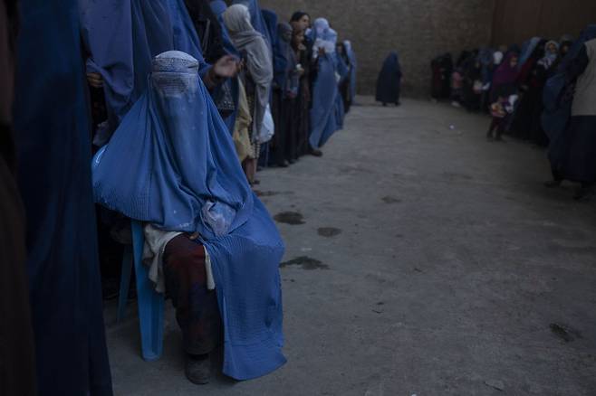 한 아프가니스탄 여성이 지난 20일(현지시간) 세계식량기구(WFP)로부터 지원금을 받기 위해 카불의 한 거리에서 대기하고 있다. 카불|AP연합뉴스
