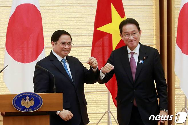 24일 팔꿈치 인사를 하고 있는 팜 민 찐 베트남 총리(왼쪽)와 기시다 후미오 일본 총리. © 로이터=뉴스1