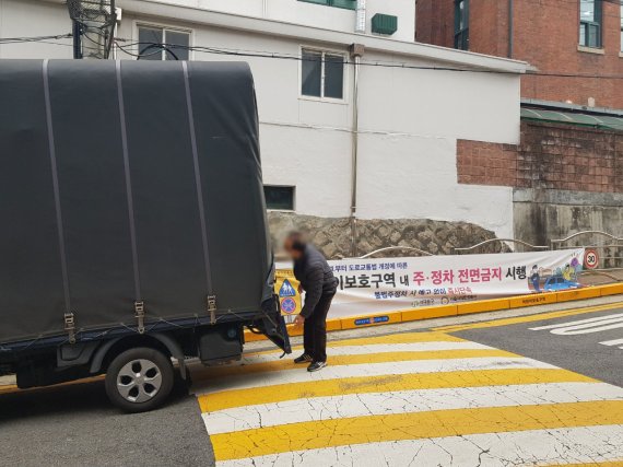 지난 24일 서울 서대문구 한 초등학교 앞에서 60대 남성이 트럭을 정차시킨 뒤 물건을 옮기고 있다. 트럭 뒤에는 '어린이보호구역 내 주·정차 전면금지 시행'이라는 현수막이 붙어있다. /사진=윤홍집 기자