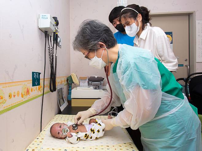 지난 10월 5일 건우가 퇴원하고 처음으로 김애란 교수와 다시 만났다. 대기실에서 낯가림으로 맹렬하게 울던 건우는 신기하게도 김 교수가 진료를 보자 울음을 뚝 그쳤다. 건우의 엄마·아빠(맨 오른쪽)는 “우리 아이 살린 것 보고 다른 사람들도 포기하지 않고 (병원에) 많이 왔으면 좋겠다”고 했다. /이신영 영상미디어 기자