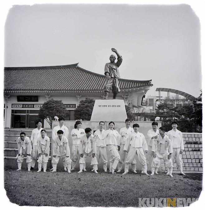 택견원 초입 잔디밭에 세워진 송암 신한승 명인 동상 앞에서 기념촬영하는 단원들