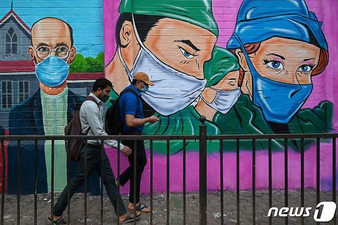30일(현지시간) 인도 뭄바이 한 거리에서 마스크를 쓴 두 남성이 걸어가고 있다. 2021.11.30 © AFP=뉴스1