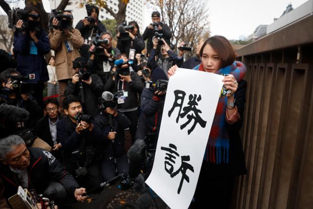 일본 미투운동의 상징인 저널리스트 이토 시오리가 2019년 12월 18일 도쿄 지방재판소에서 열린 성폭행 피해에 대한 손해배상 청구소송에서 승소한 뒤 '승소'라고 적힌 종이를 들고 소감을 밝히고 있다. 도쿄=AP 연합뉴스