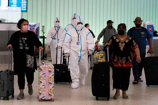 지난달 30일 미 LA국제공항에 도착한 에어차이나의 승무원들이 방호복을 입은 채로 다른 여행객들과 함께 입국하고 있다. 캘리포니아에선 1일 남아공을 다녀온 주민이 미국 첫 오미크론 감염자로 확인됐다. /AP 연합뉴스