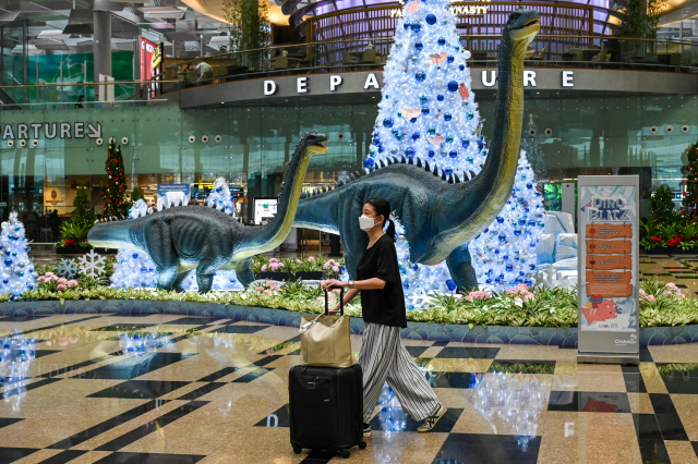 2일 싱가포르 창이 국제공항에서 한 여성이 마스크를 착용한 채 걷고 있다. 이날 싱가포르 보건부는 전날 남아프리카공화국 요하네스버그에서 출발한 항공편을 이용해 싱가포르에 입국한 승객 2명이 오미크론에 감염되니 것으로 확인됐다고 밝혔다./AFP연합뉴스