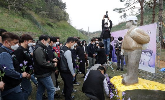 지난 4월 28일 충남 태안화력발전소 정문에서 열린 '청년비정규직 고(故 )김용균 추모조형물 제막식'에서 참석자들이 故김용균를 추모하며 조형물 앞에 꽃을 꽂고 있다. 뉴스1