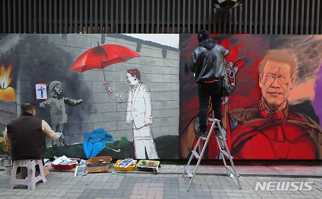 [서울=뉴시스] 배훈식 기자 = 보수와 진보성향 탱크시(왼쪽), 닌볼트 그래비티 작가가 5일 오후 서울 종로구의 한 중고서점 외벽에 각각 이재명 더불어민주당 대선 후보와 윤석열 국민의힘 대선후보의 벽화를 그리며 아트배틀을 펼치고 있다. 2021.12.05. dahora83@newsis.com