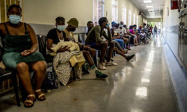 1일(현지시간) 남아프리카공화국 요하네스버그 인근 한 병원에 코로나19 백신을 접종하려는 시민들이 줄지어 앉아 있다. 요하네스버그=AP뉴시스