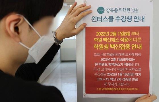 7일 서울 마포구 종로학원 강북본원에서 직원이 방역패스 관련 안내문을 부착하고 있다.   연합뉴스