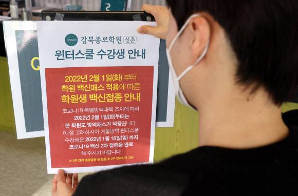 학원 방역패스 적용에 따른 안내문 - 7일 서울 마포구 종로학원 강북본원에서 직원이 방역패스 관련 안내문을 부착하고 있다.      정부가 학생과 학부모들의 반발에도 내년 2월부터 식당?카페?학원?도서관 등을 이용하는 12~18세 청소년에게도 방역패스를 적용한다고 밝히면서, 학생과 학부모들을 중심으로 ‘미접종자에 대한 차별이자 학습권 침해, 사실상 접종 강요’라는 움직임이 거세지고 있다. 2021.12.7 연합뉴스