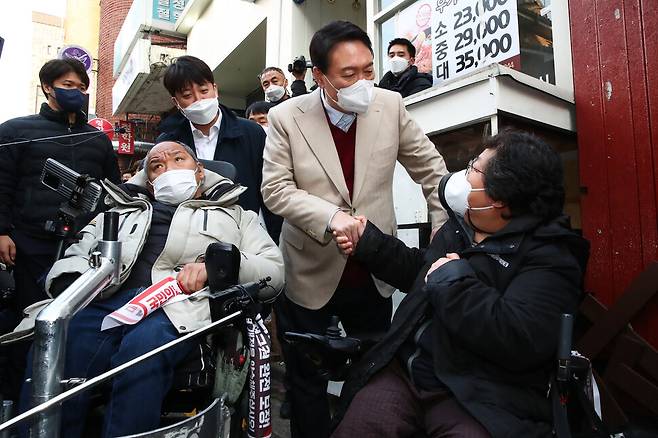 국민의힘 윤석열 대선후보(가운데)와 이준석 대표(왼쪽)가 8일 오후 서울 종로구 대학로 거리 플랫폼74에서 열린 청년문화예술인간담회에 참석하기 전 입구에서 윤 후보와 면담을 요구하던 장애인 단체 회원과 대화하고 있다. 국회사진기자단