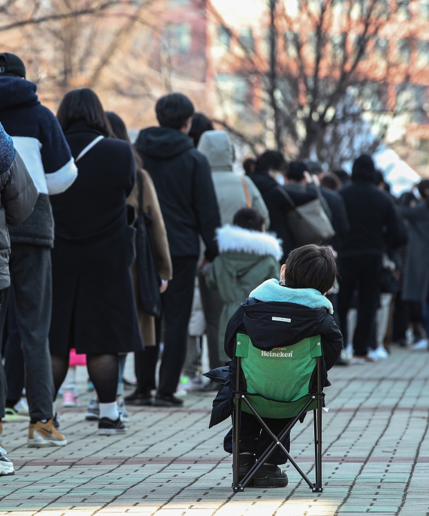 신종 코로나바이러스 감염증(코로나19) 신규 확진이 사상 최다인 7천175명을 기록한 8일 오후 서울 마포구 경의선 서강대역 인근 선별진료소에서 한 어린이가 긴 줄 사이에 휴대용 의자에 앉아 차례를 기다리고 있다. /사진=연합뉴스