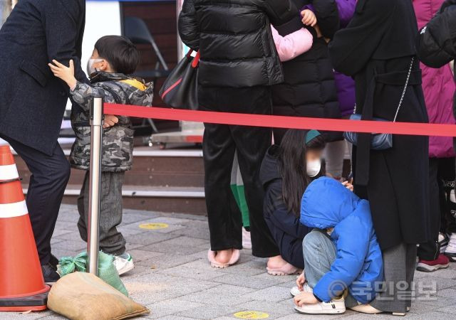 8일 서울 송파구보건소 앞에서 코로나19 선별 검사를 받기 위해 방문한 어린이들이 지친 기색으로 쪼그려 앉아있다.