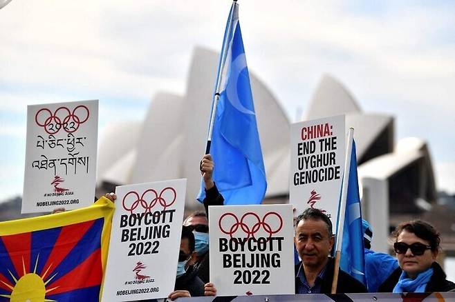 지난 6월 오스트레일리아 시드니에서 베이징 겨울올림픽 보이콧을 주장하는 시위자들이 손팻말을 들고 있다. 시드니/AFP 연합뉴스